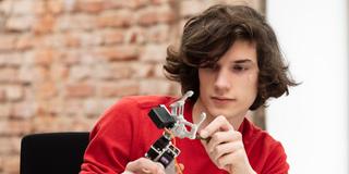Ein Jugendlicher bastelt an einem Roboterarm. (Foto: picture alliance / Westend61 | Studio 27)