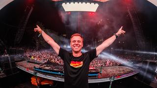 Ein Dj vor dem DJ-Pult, im Hintergrund Publikum (Foto: Pressefoto/Armin van Buuren)