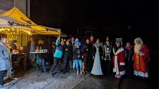 Eine Gruppe Menschen in winterlicher Kleidung, teilweise als Nikolaus verkleidet, stehen draußen im Schnee. (Foto: UNSERDING)