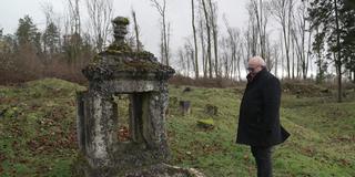 Mann steht auf einer Wiese vor einem alten Brunnen. (Foto: SR)