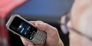 Ein älterer Menschen sitzt in seiner Wohnung und hält ein Telefon in der Hand. (Foto: Imago/Fotostand/K. Schmitt)