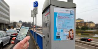 Jemand bucht ein Parkticket mit dem Smartphone vor einem Parkscheinautomat in Saarbrücken (Foto: IMAGO / BeckerBredel)