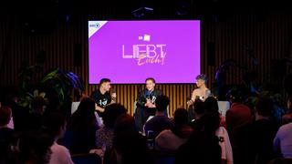 Blick auf eine Bühne, auf der drei personen sitzen. Im Hintergrund ist ein lila "Liebt Euch" Poster zu sehen. (Foto: Liebt Euch Podcast)