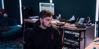 Martin Garrix sitzt in einem Studio und schaut seitlich auf einen Bildschirm. (Foto: Presse)