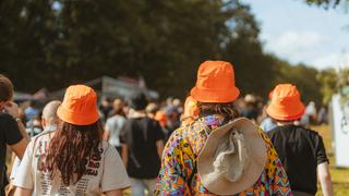 Drei Personen mit orangenen Hüten laufen in einer Menge. (Foto: MXM Photo)