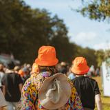 Drei Personen mit orangenen Hüten laufen in einer Menge. (Foto: MXM Photo)